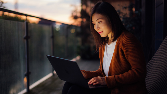 Woman typing on laptop balcony